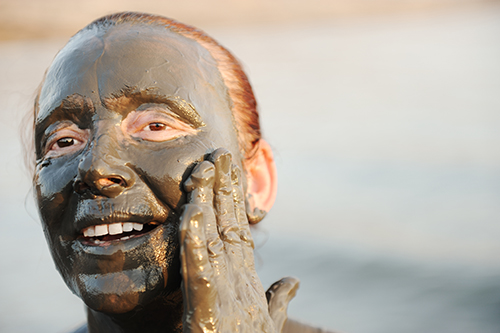 Elderly woman in a bathing suit of natural mineral mud sourced from the dead sea in Jordan