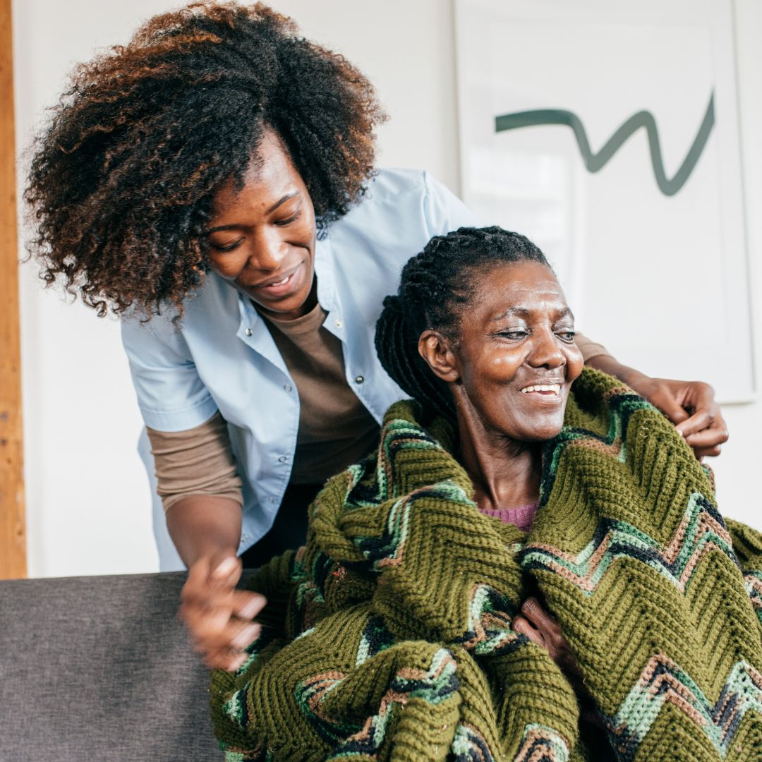 a caregiver covering a patient in a knitted green blanket