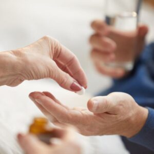 A person handing a senior their meds