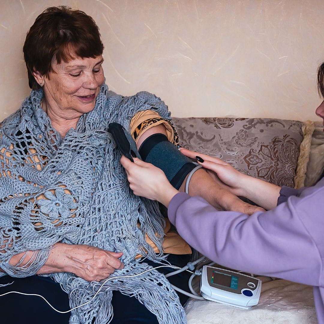 woman checking an elderly woman's blood pressure