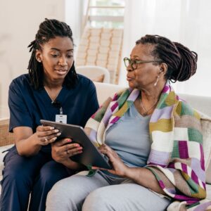 Nurse sitting next to person she is helping